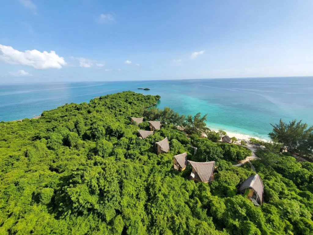 Aerial view of eco-lodge bungalows on a forested tropical island with turquoise waters