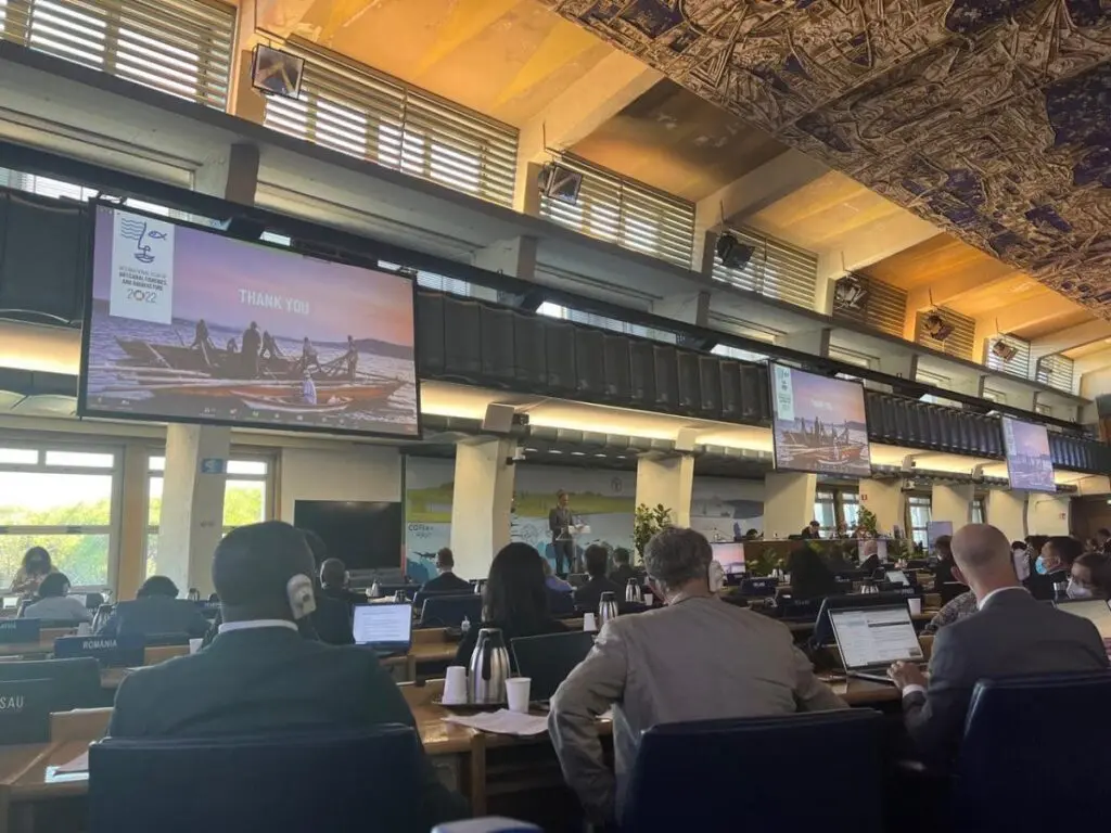 Conference hall with delegates and screens showing a presentation slide