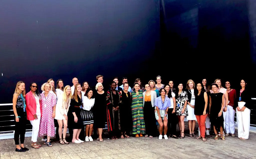 A large group of people posing together outdoors in front of a ship's hull.