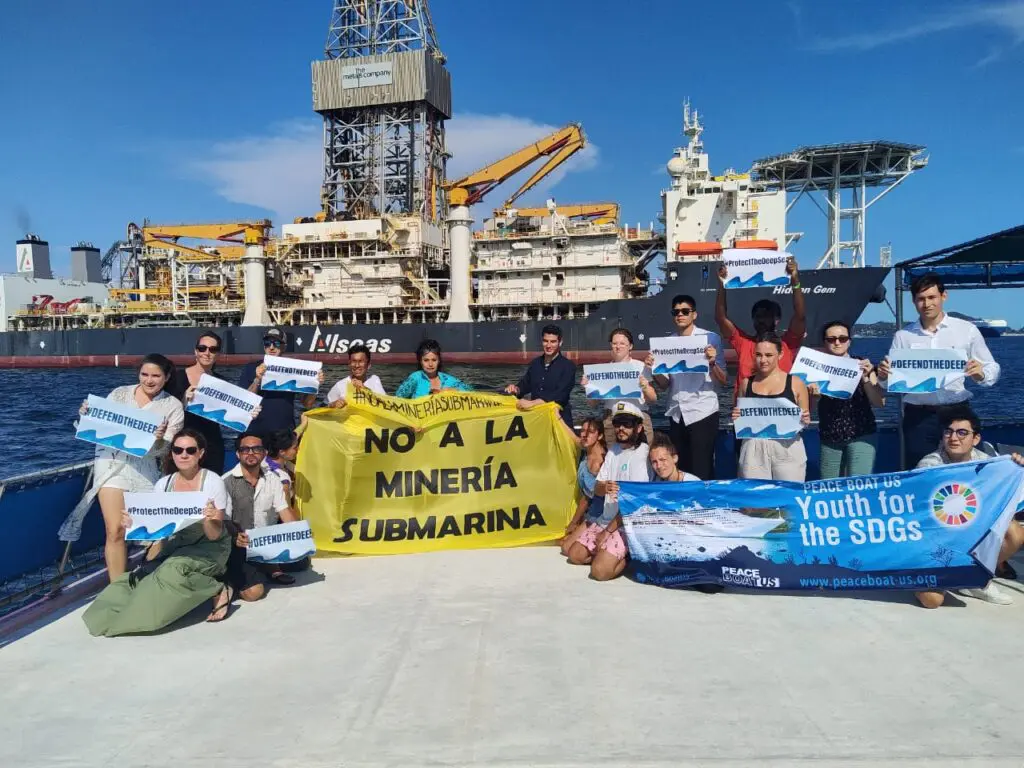 Activists with anti-deep-sea-mining banners on a ship's deck.
