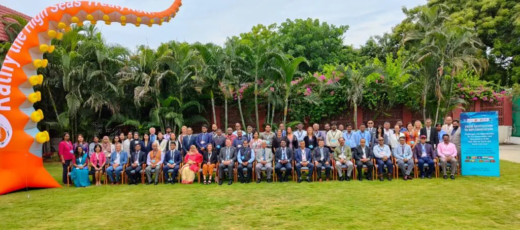 Large group of delegates posing outdoors with a Ratify the High Seas Treaty Now inflatable and workshop banners