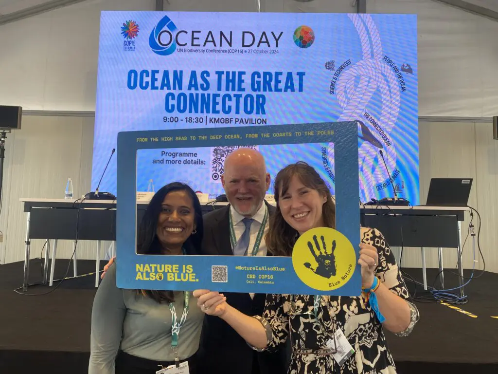 Three people holding an Ocean Day photo frame at COP16