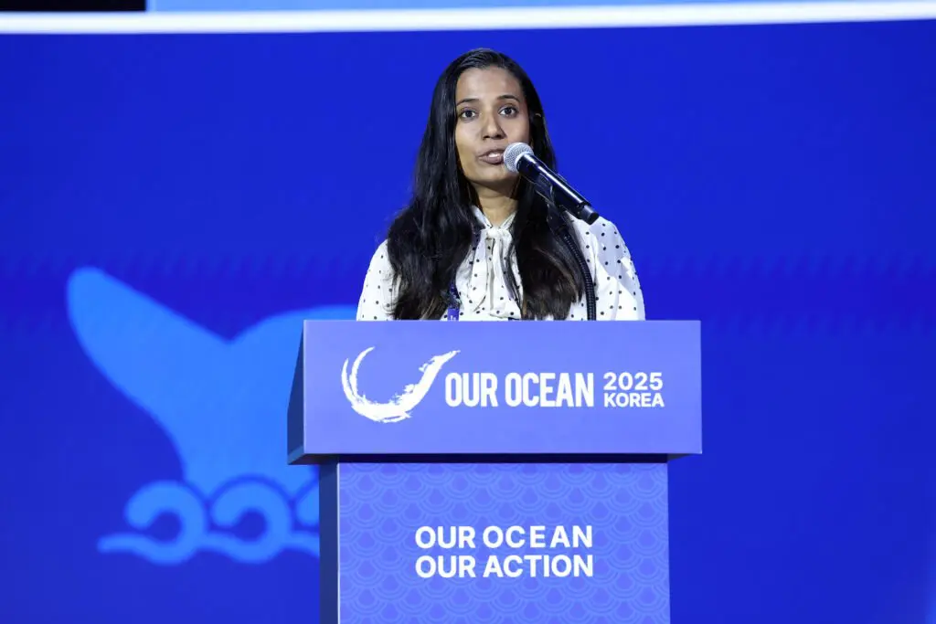 A woman speaking at a podium at the Our Ocean 2025 Korea conference.