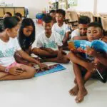 A group of children sitting on the floor reading illustrated ocean storybooks.