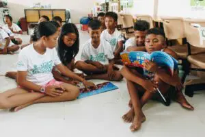 A group of children sitting on the floor reading illustrated ocean storybooks.