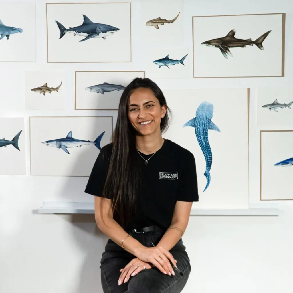 Woman seated in front of a wall of framed shark illustrations
