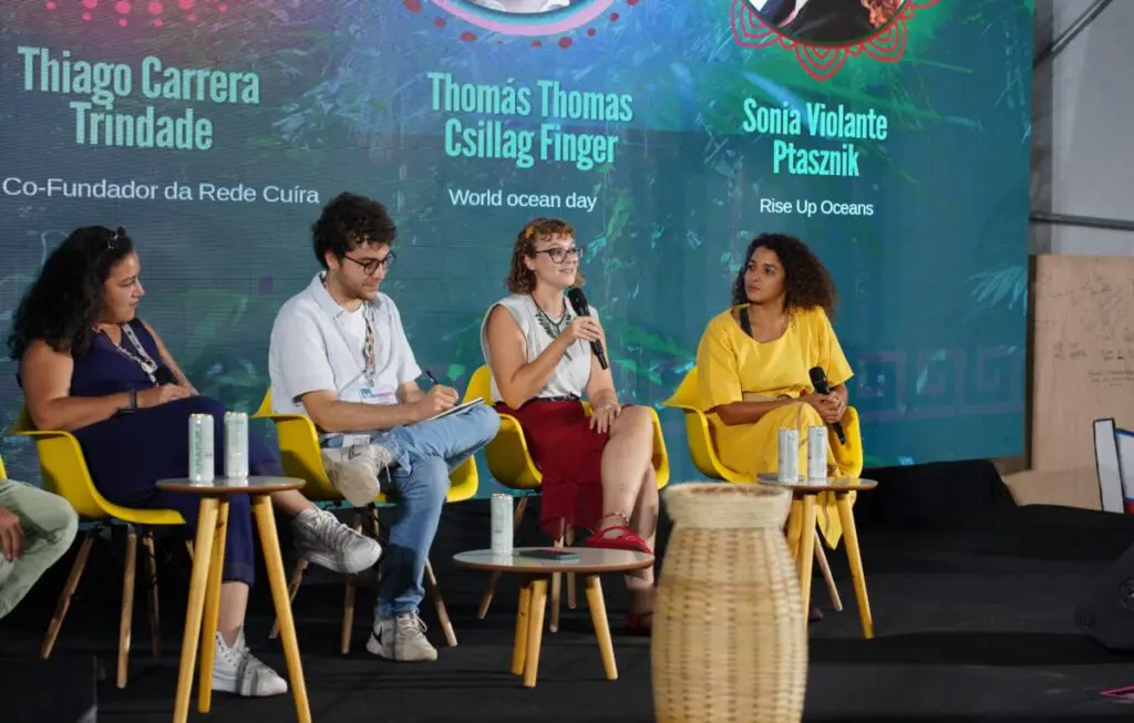 Four panellists seated on stage with microphones during a conference session